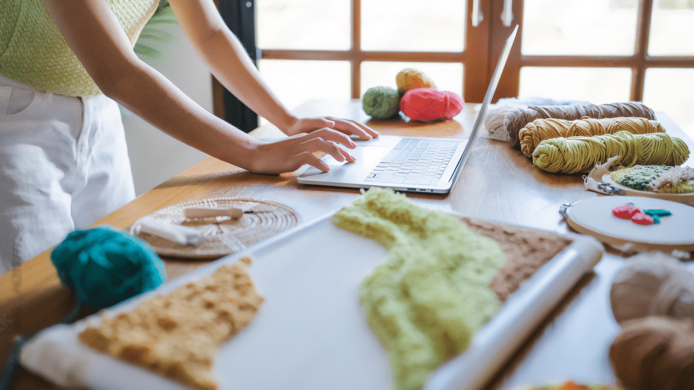 Holiday-themed gifts wrapped in brown paper with red ornaments, pine needles, and pinecones on a wooden surface against a dark green background